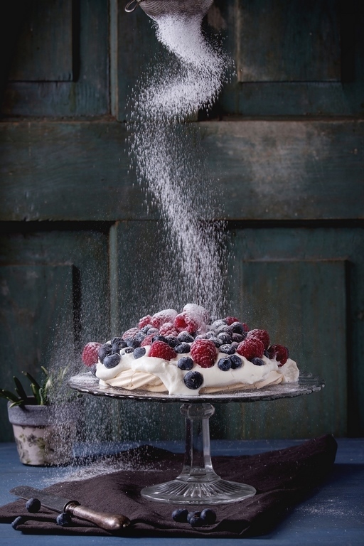 500px Photo ID: 139471969 - Vintage cake stand with Meringue dessert Pavlova with fresh blackberries and raspberries, strewing by sugar powder. Over blue wooden table. Dark rustic style.