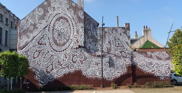 Artista pinta con aerosol un mural de encaje en un museo francés